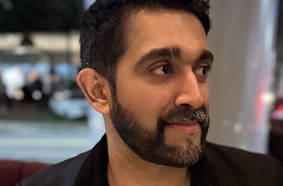 Close-up of a man with dark hair and a groomed beard looking off-camera.