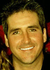 A close-up portrait of a smiling man with short, dark, spiked hair.