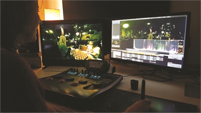A person uses a control surface and dual monitors to edit video footage in a dimly lit room.