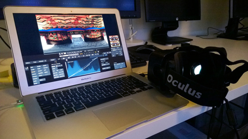 A laptop showing video editing software on its screen next to a black Oculus VR headset on a white desk.