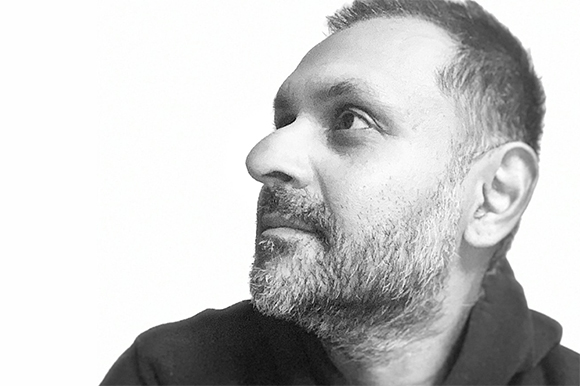 Black and white profile portrait of a man with a beard looking up against a white background.