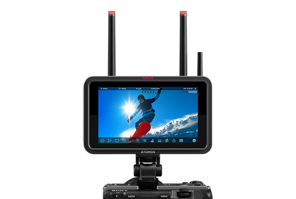 Atomos Ninja monitor with two antennas mounted on a camera, displaying a person snowboarding against a bright sky.
