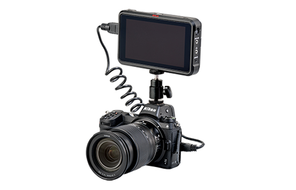 A black Nikon digital camera with a large lens and an external monitor attached to the top via a mounting arm.