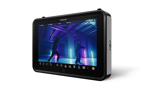A black Shogun video monitor displaying a scene of two people dancing in a blue-lit studio.