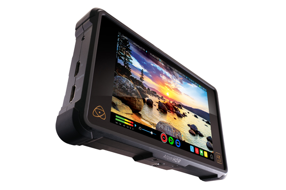 A black Atomos Atom HDR field monitor displaying a sunset landscape over a rocky coastline.