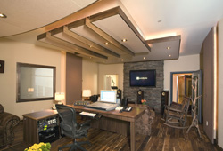 A professional studio workspace featuring a large wooden desk, computer, and recessed ceiling lighting.