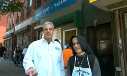 A man in a white button-down shirt and a nun in a black habit stand on a city sidewalk.