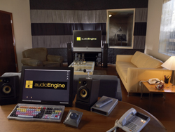 A studio room with a monitor, speakers, a sofa, and an armchair.