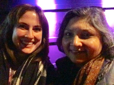 Two women smiling at the camera, with a purple illuminated background.
