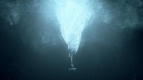 A bright, swirling column of bubbles rising from the darkness toward a light source underwater.