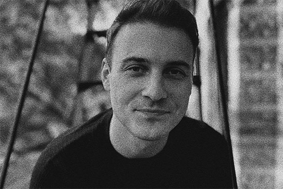 Black and white close-up portrait of a man with short hair smiling slightly.