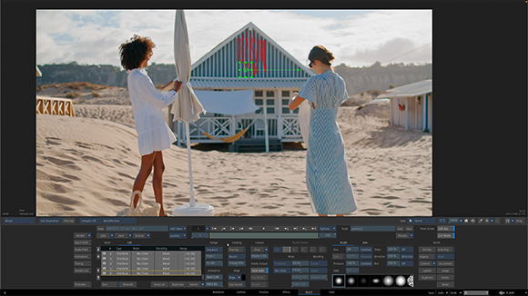 Two women stand on a sandy beach near a white beach hut and a large closed umbrella.