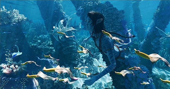 A blue-skinned humanoid swims through a vibrant underwater coral reef surrounded by glowing fish.