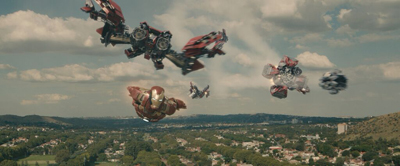 Multiple red and silver armored figures flying through a cloudy sky over a green landscape.