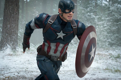 A man in a blue, red, and white superhero suit runs through a snowy forest holding a circular shield.