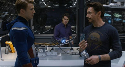 A man in a blue superhero suit faces a man in a dark long-sleeve shirt in a futuristic lab.