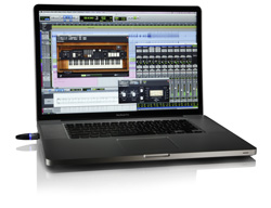 A laptop on a white surface showing a music production software interface with a virtual keyboard plugin.