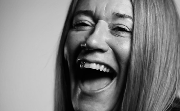 Black and white close-up of a woman laughing with her mouth wide open.