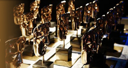 Multiple golden mask-shaped trophies arranged in rows on a table under warm lighting.