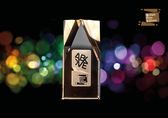A rectangular metallic trophy with a black center and text, set against colorful bokeh lights.