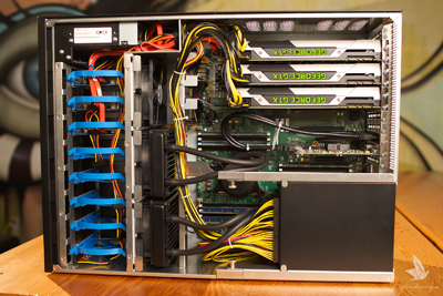 Open computer case showing multiple graphics cards, yellow and black power cables, and blue drive bays.