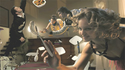 People reach toward floating plates of food and silver spoons in a surreal, dreamlike kitchen scene.