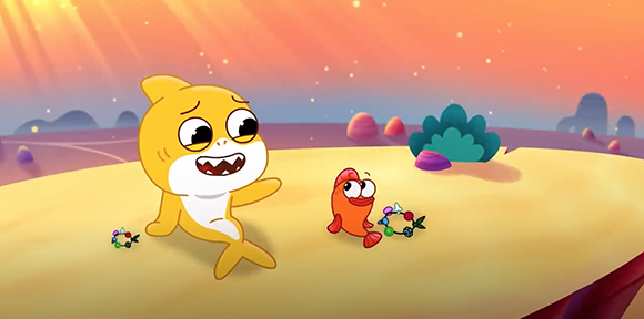 Animated yellow shark and small orange fish on a sandy landscape under a sunset sky.