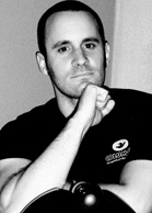 Black and white portrait of a man with short hair resting his chin on his hand.