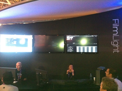 People observe screens displaying graphics and video at a FilmLight booth.