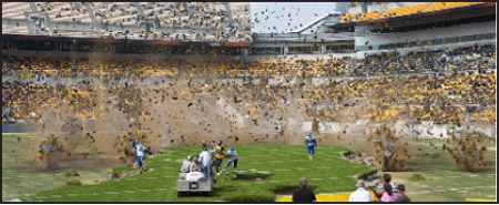Dirt and debris fly through the air above a football field in a crowded stadium.