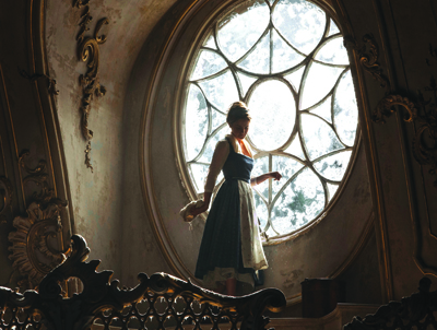 Silhouette of a woman in a blue and white dress standing before a large, ornate circular window.