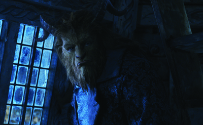 A creature with horns and fur looking toward the camera in a dark, blue-lit room.