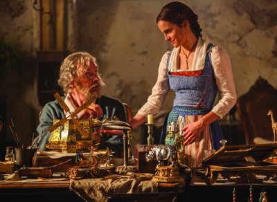 A woman in a blue and white dirndl looks down at a seated man surrounded by intricate mechanical trinkets.