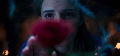 A woman's eyes peering through a blurry red flower in a dark, dimly lit setting.