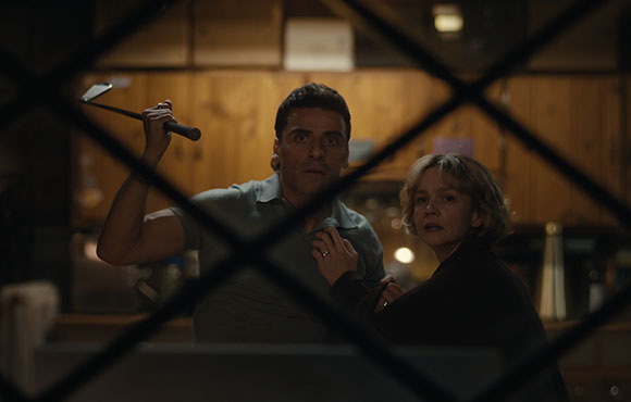 A man raises a hammer while a woman looks on with a worried expression through a diamond-patterned window.