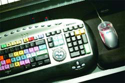 A specialized video editing console with many colored buttons next to a silver computer mouse.