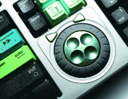Close-up of a computer keyboard featuring green, blue, and black keys and a circular control button.