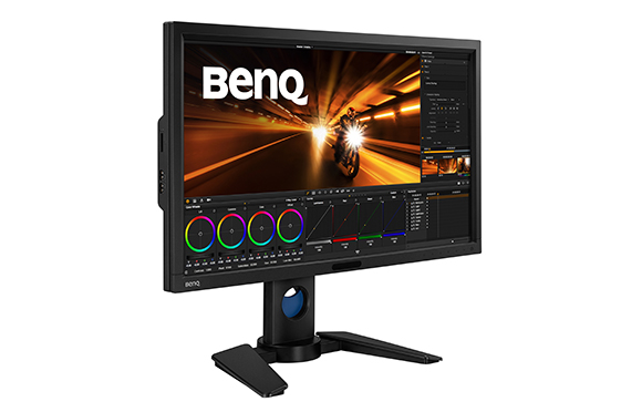 A black BenQ professional monitor on a stand displaying video editing software with color wheels and timelines.
