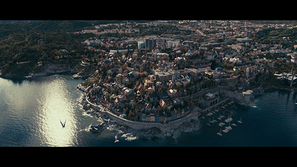 Aerial view of a dense coastal city with stone walls and buildings nestled on a rocky peninsula by the sea.