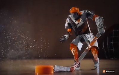 A stylized figure in orange and grey hockey gear maneuvers a hockey stick toward an orange puck.
