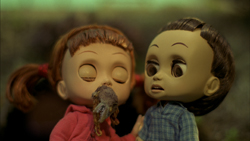 Two small dolls with large eyes and pigtails looking at one another.