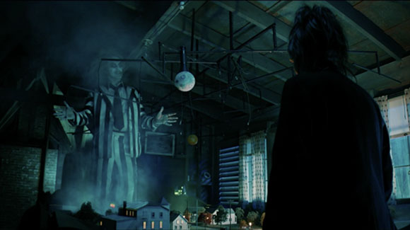 A person in silhouette watches a large, translucent figure looming over a miniature model town.