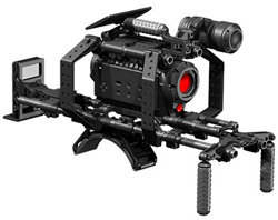 A professional black cinema camera rig with a lens, monitor, and handgrips on a white background.