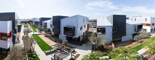Modern multi-story buildings with white, black, and red facades surrounding landscaped walkways and green lawns.