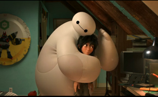 A large, white, soft inflatable robot gives a warm hug to a young boy with dark hair in a dimly lit room.