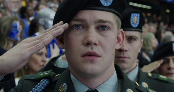 A young man in a dark beret and green military uniform salutes while crying.