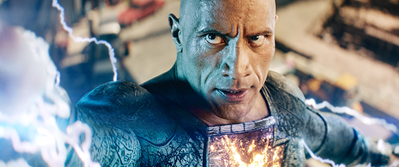 A man in a dark, textured superhero suit with glowing orange energy on his chest and blue lightning around him.
