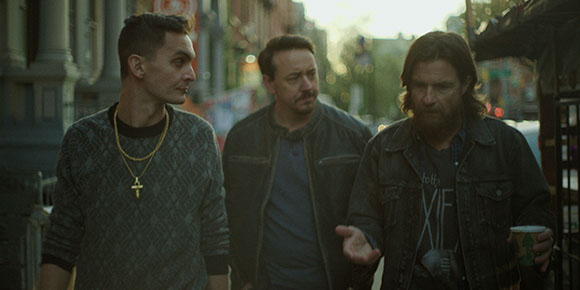 Three men walk along a city street during the day.