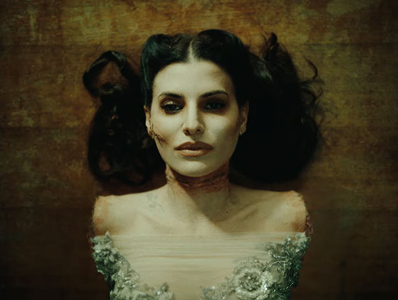 A woman with dark hair and pale skin lies against a textured brown background.
