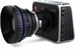 A black digital camera with a large, prominent lens and silver accents.
